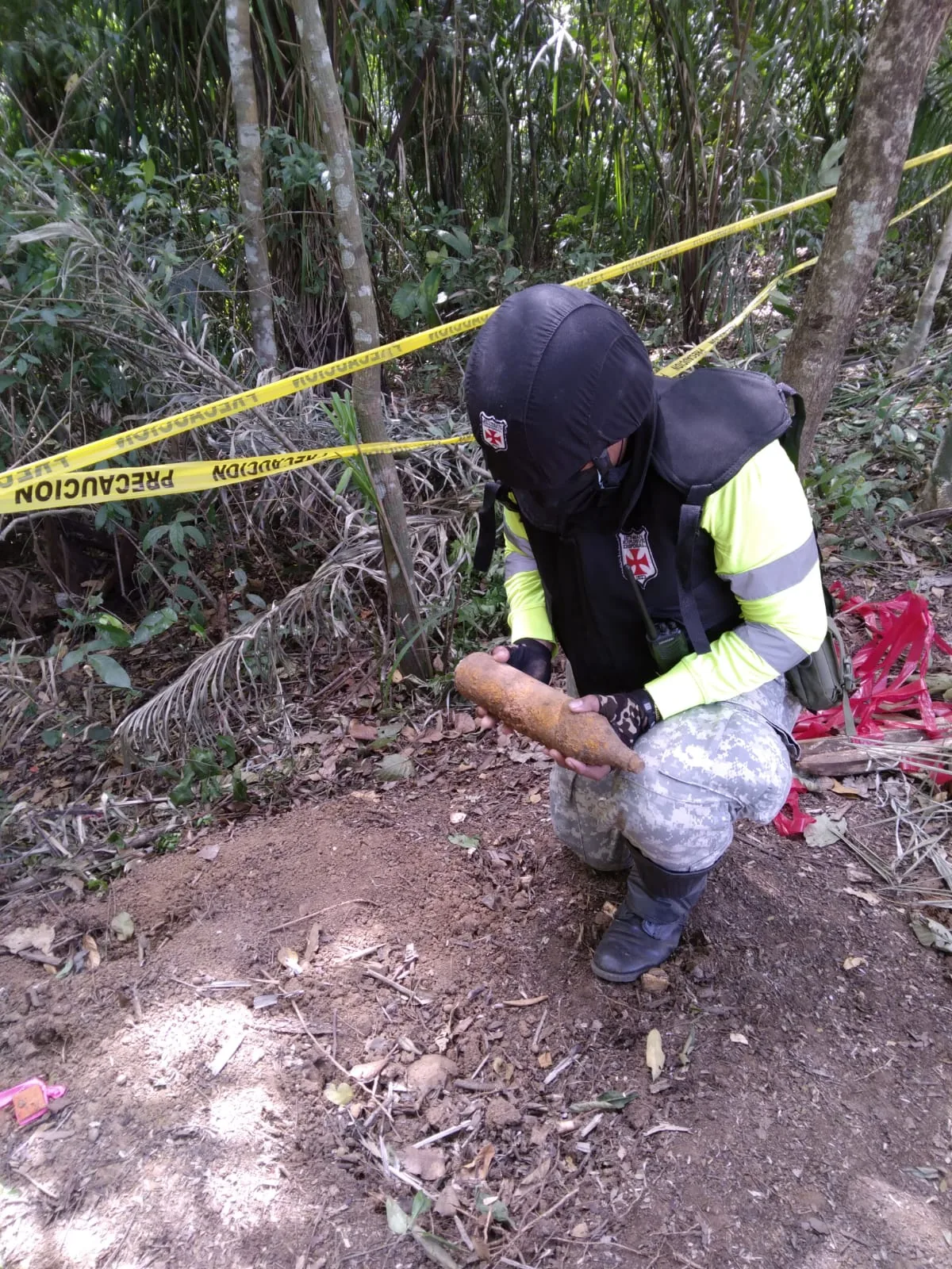 Especialista recuperando manualmente una munición en vegetación densa